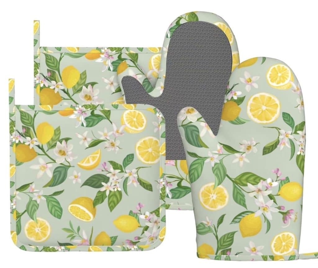 Two oven mitts and two pot holders with a light green background featuring lemons, lemon slices, and white flowers—perfect for baking your favorite flower cookies recipe. The mitts have a gray textured palm area.